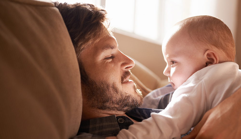 father and bonding with baby on sofa in home living room